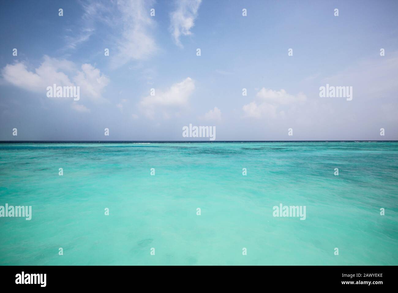 Idilliaco oceano turchese sotto cielo blu soleggiato, Maldive Foto Stock