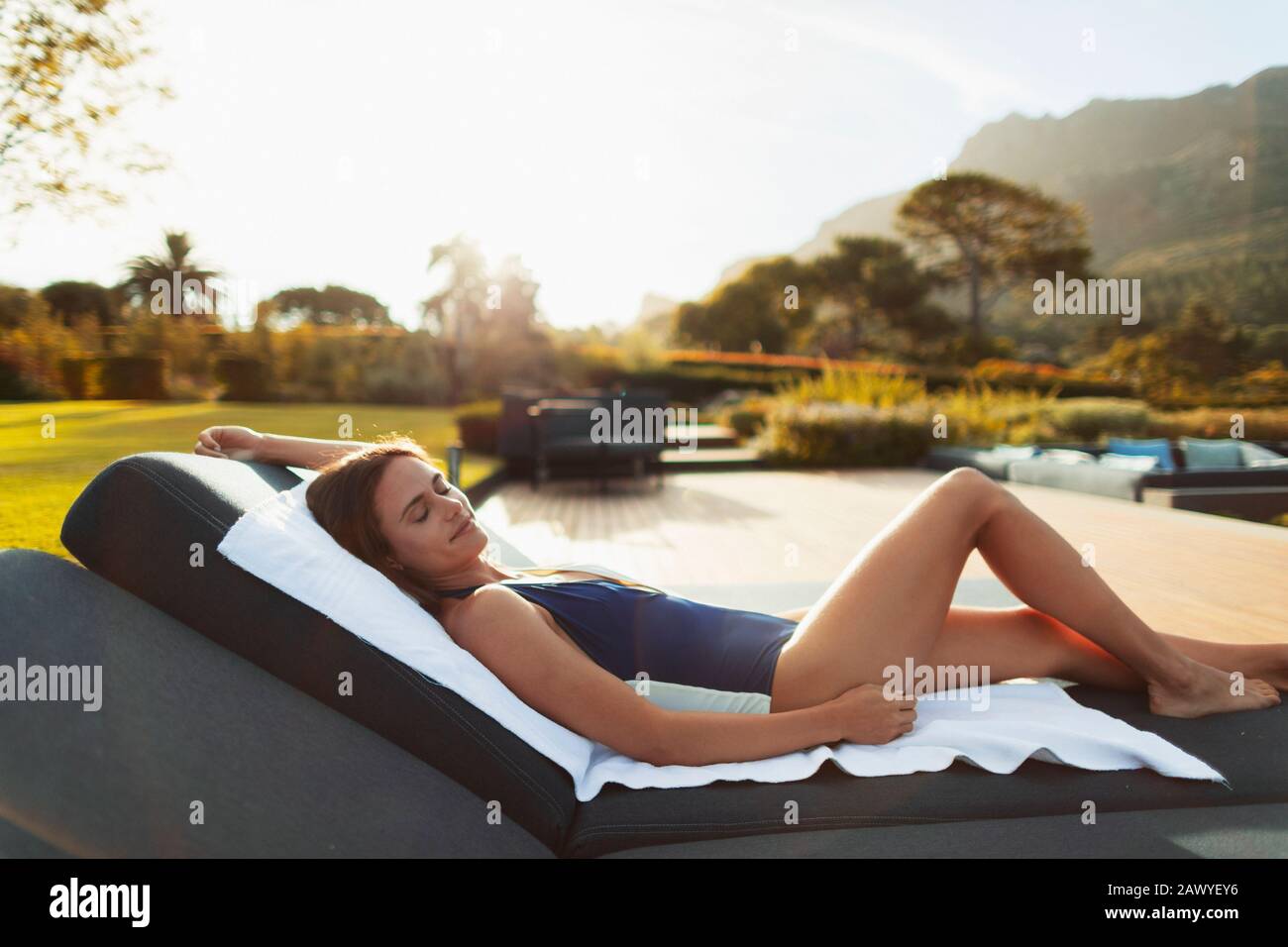 Giovane donna serena in costume da bagno rilassante, prendere il sole sul patio di lusso Foto Stock
