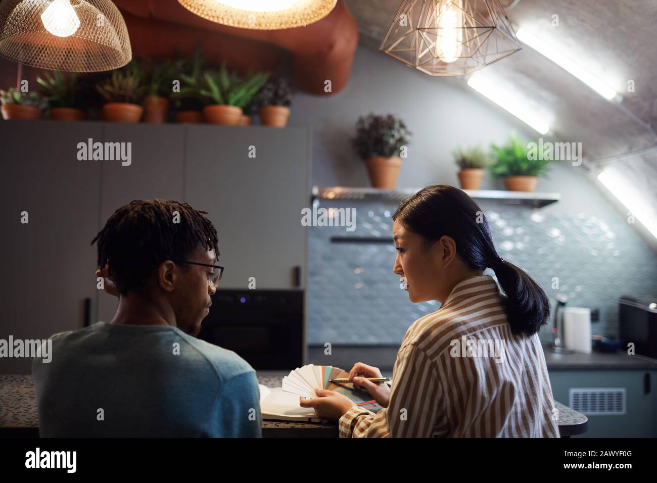Ritratto della vista posteriore di due progettisti contemporanei che discutono i campioni di colore nell'interno della cucina Foto Stock