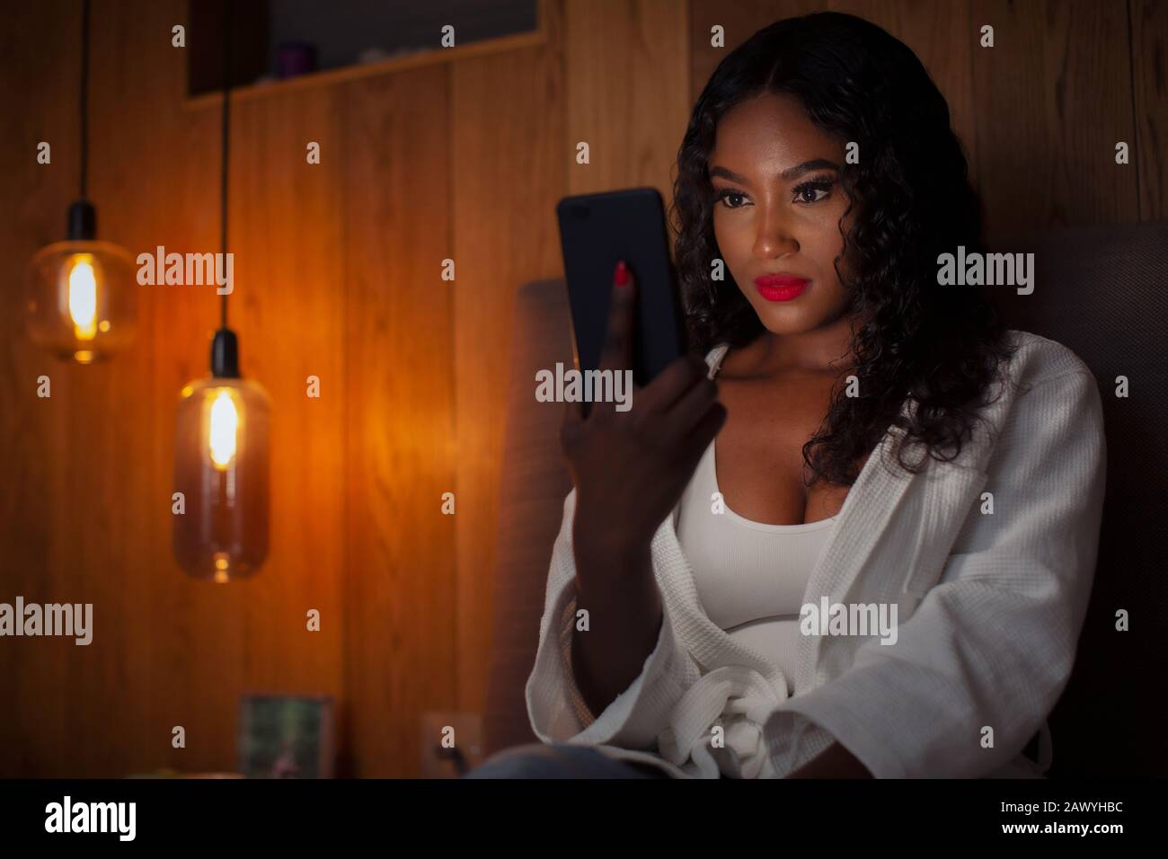 Giovane donna che usa lo smartphone in camera oscura Foto Stock