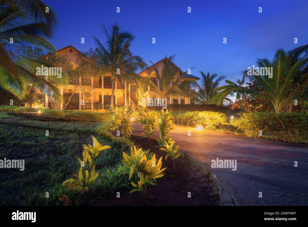 Un hotel fantastico con sentieri illuminati in un giardino di fiori nella notte estiva Foto Stock
