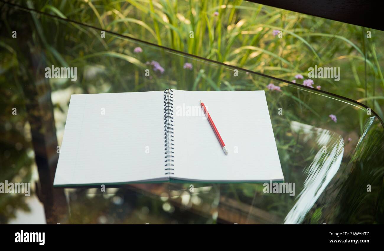 Aprire il notebook vuoto e la matita sul tavolo di vetro Foto Stock