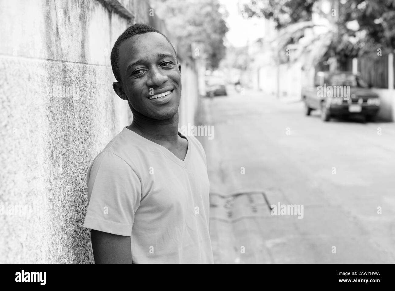 Felice giovane africano sorridente contro vecchie pareti di cemento nelle strade all'aperto Foto Stock
