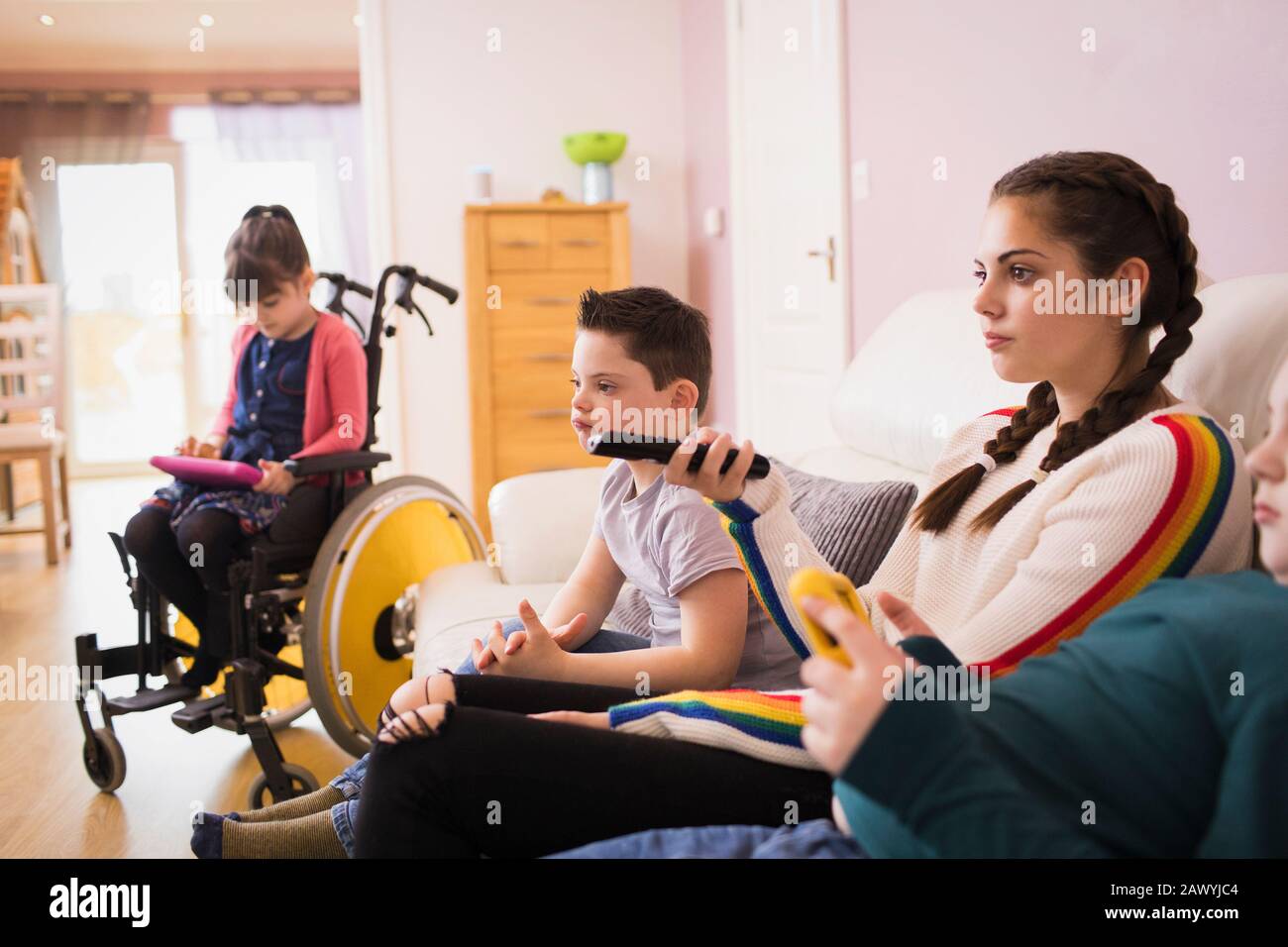 Famiglia con Sindrome Di Down bambino guardare la TV nel soggiorno Foto Stock