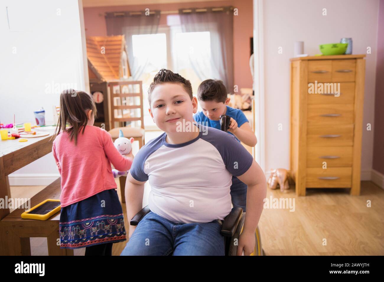 Ritratto ragazzo sorridente in sedia a rotelle a casa Foto Stock