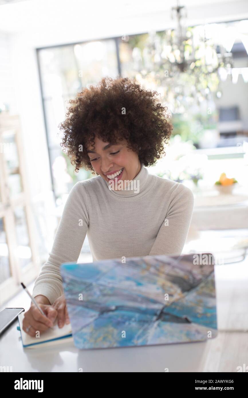 Sorridente giovane freelancer femminile che lavora a laptop in cucina Foto Stock