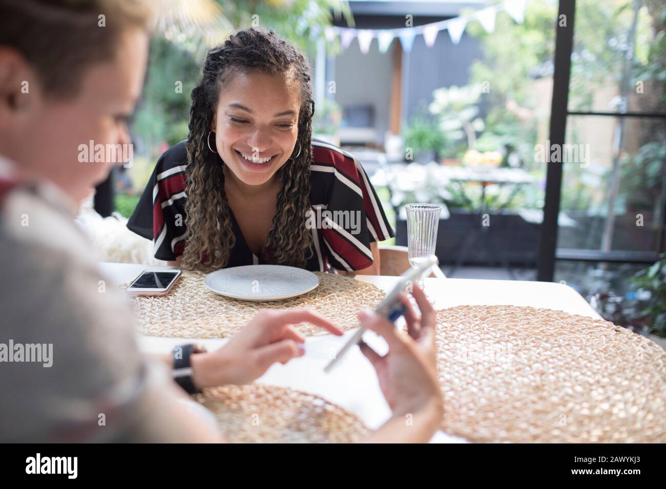 Giovani amici donne che usano lo smartphone al tavolo da pranzo Foto Stock