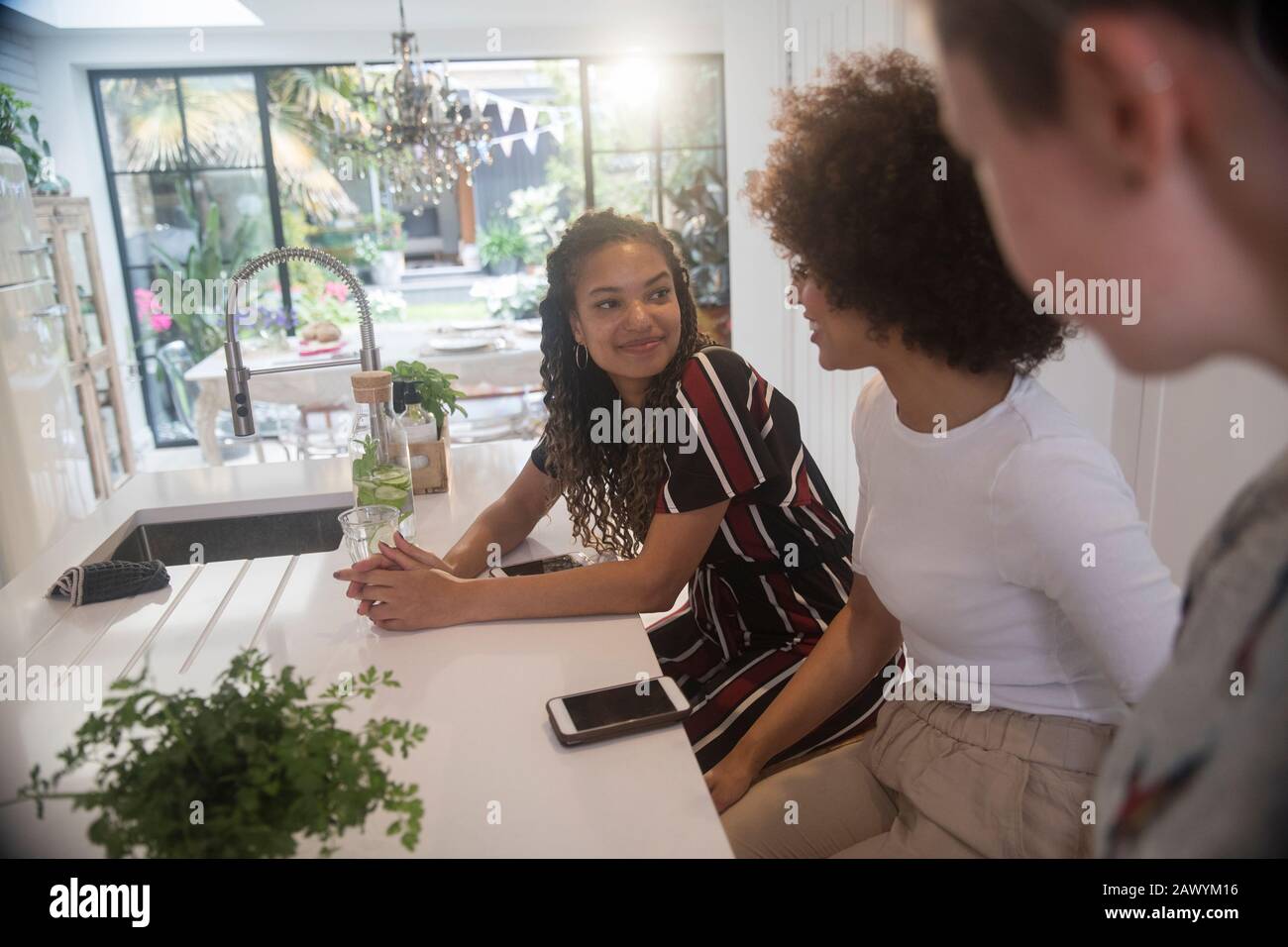 Giovani donne amici con smartphone parlare in cucina Foto Stock