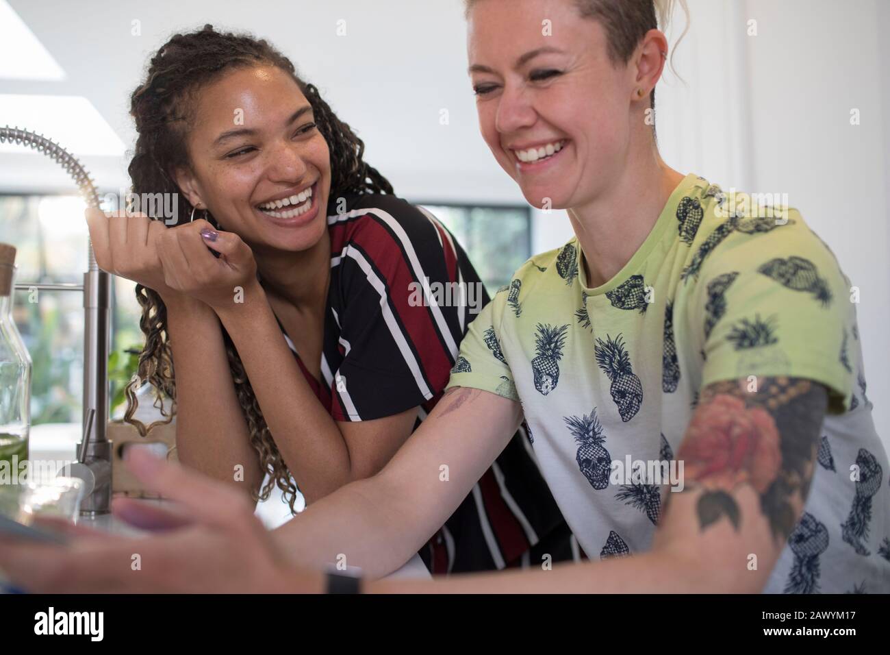 Felici giovani amici donne ridendo in cucina Foto Stock
