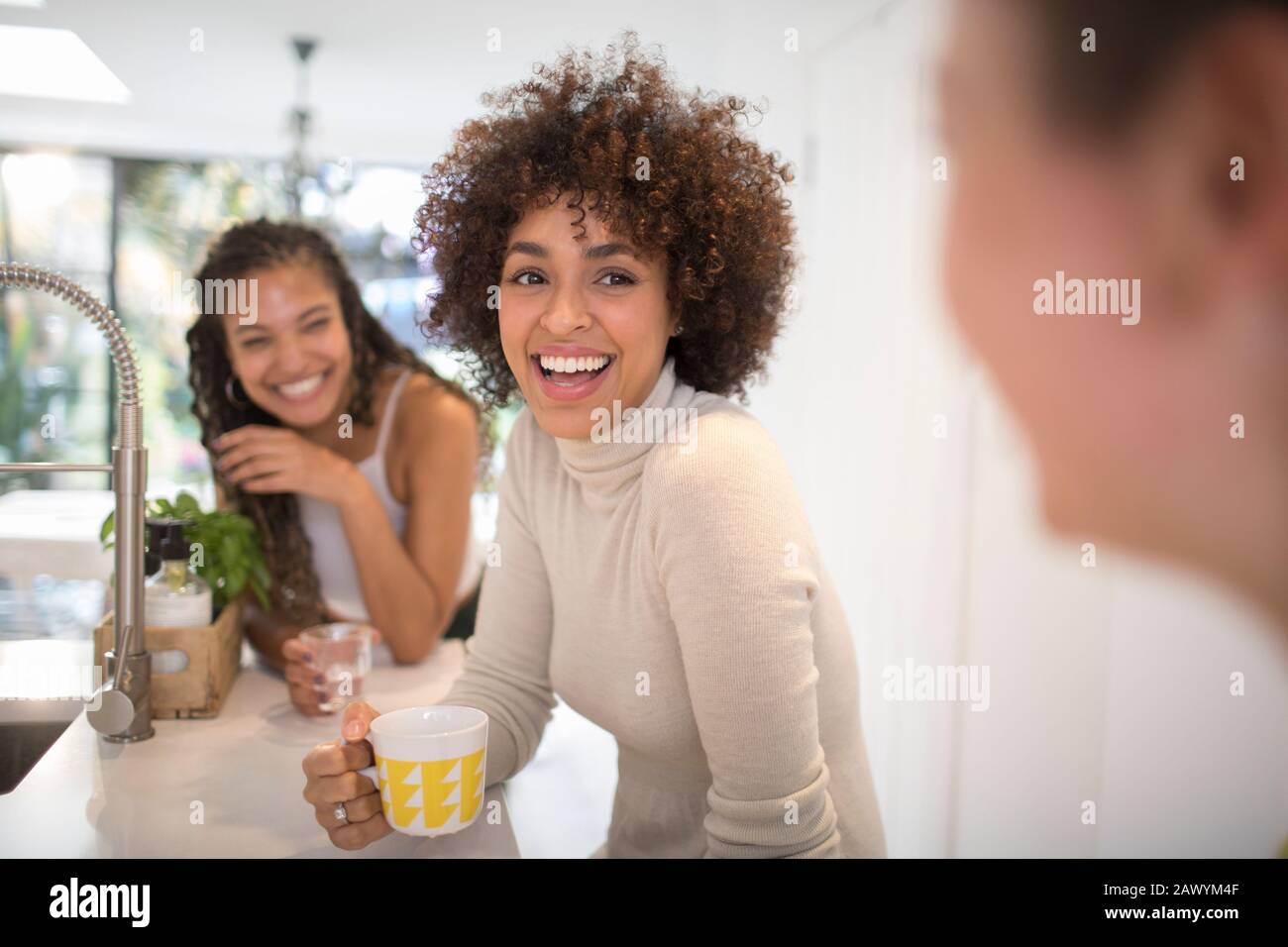 Felici giovani amici donne ridere e bere tè in cucina Foto Stock