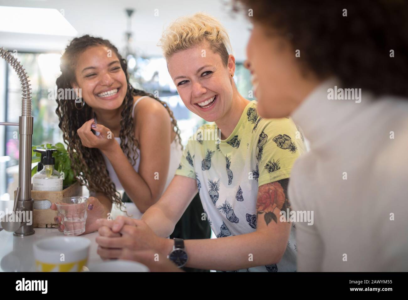 Felici giovani amici donne ridere e parlare in cucina Foto Stock