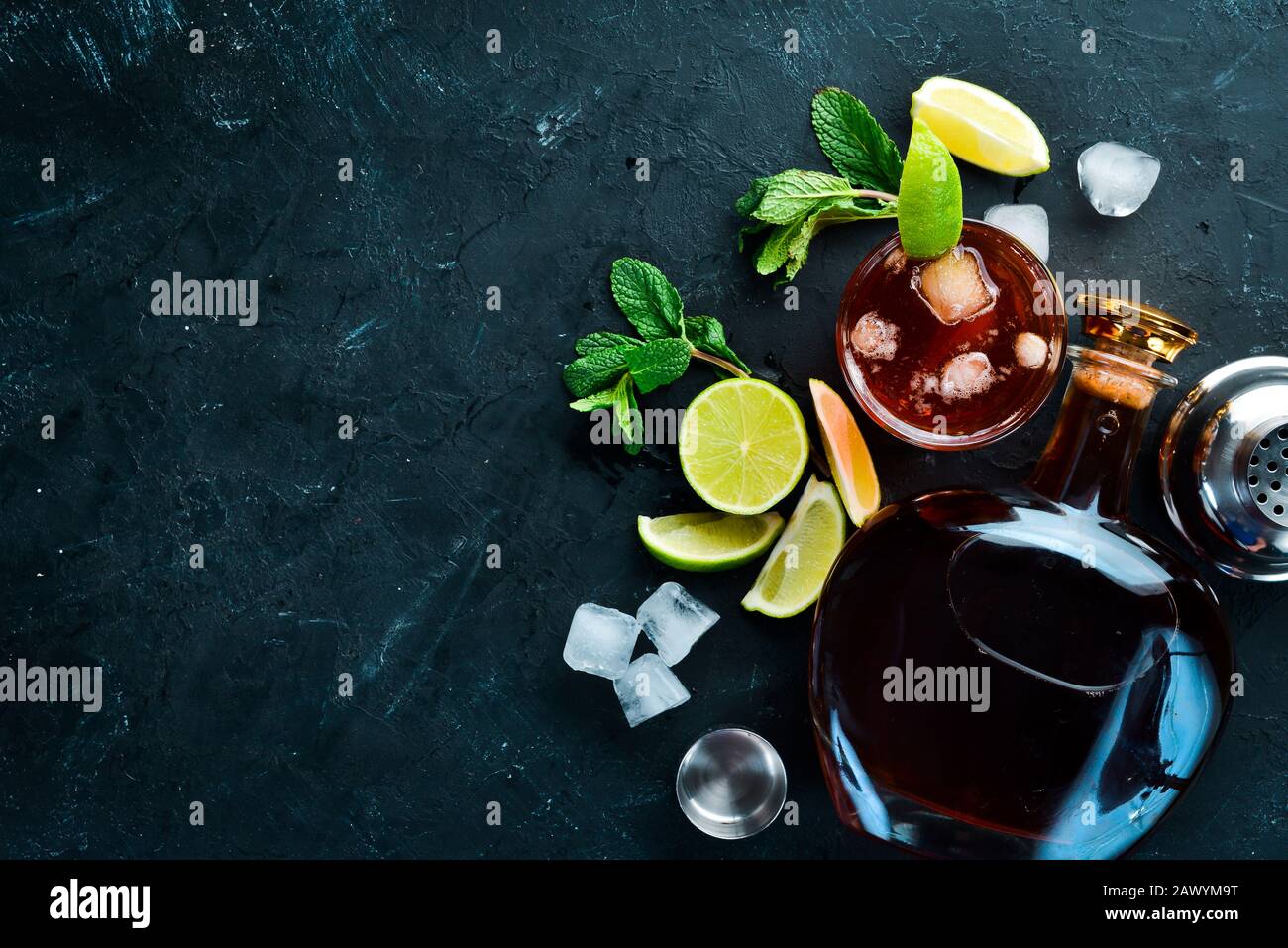 Bevande alcoliche Rum, lime e menta su sfondo di pietra nera. Vista dall'alto. Spazio libero per il testo. Foto Stock