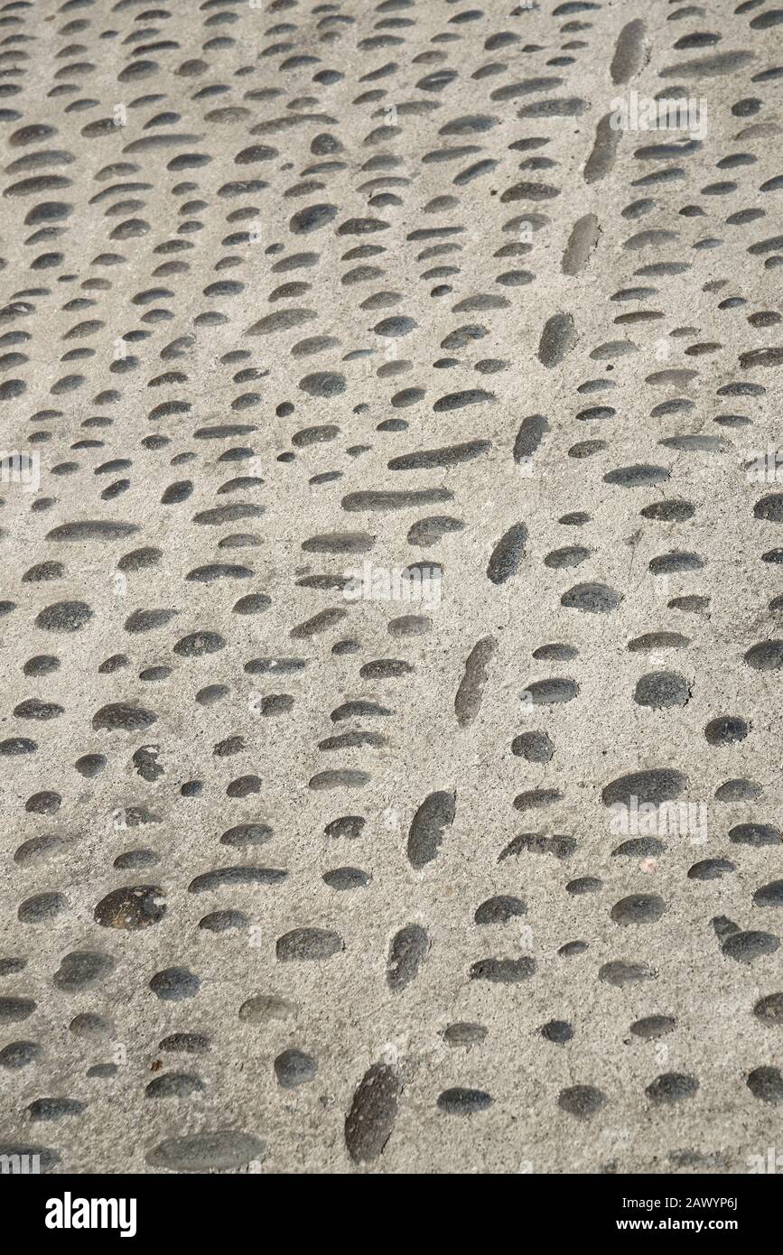 Una strada con piccole pietre nere incastonate in cemento. Superficie stradale acciottolata. Foto Stock