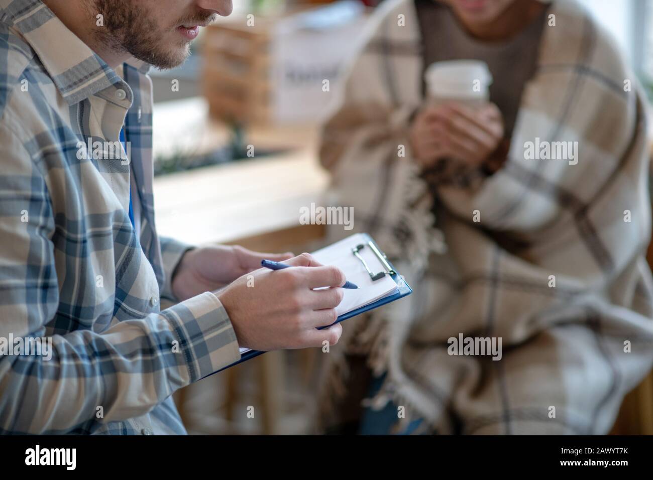 Giovane che tiene un notebook e una penna, scrivendo. Foto Stock