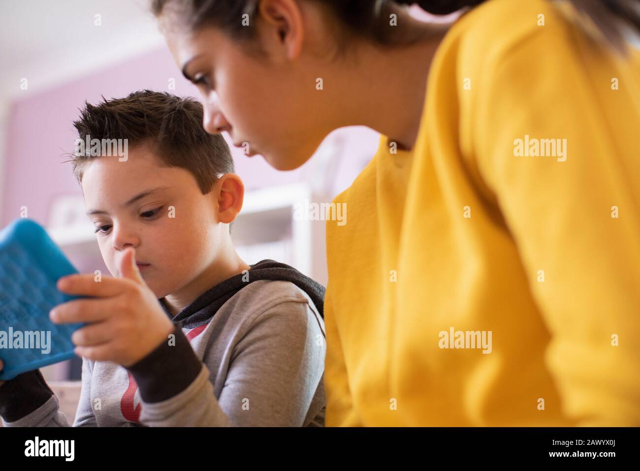 Sorella e fratello con sindrome Di Down utilizzando un tablet digitale Foto Stock