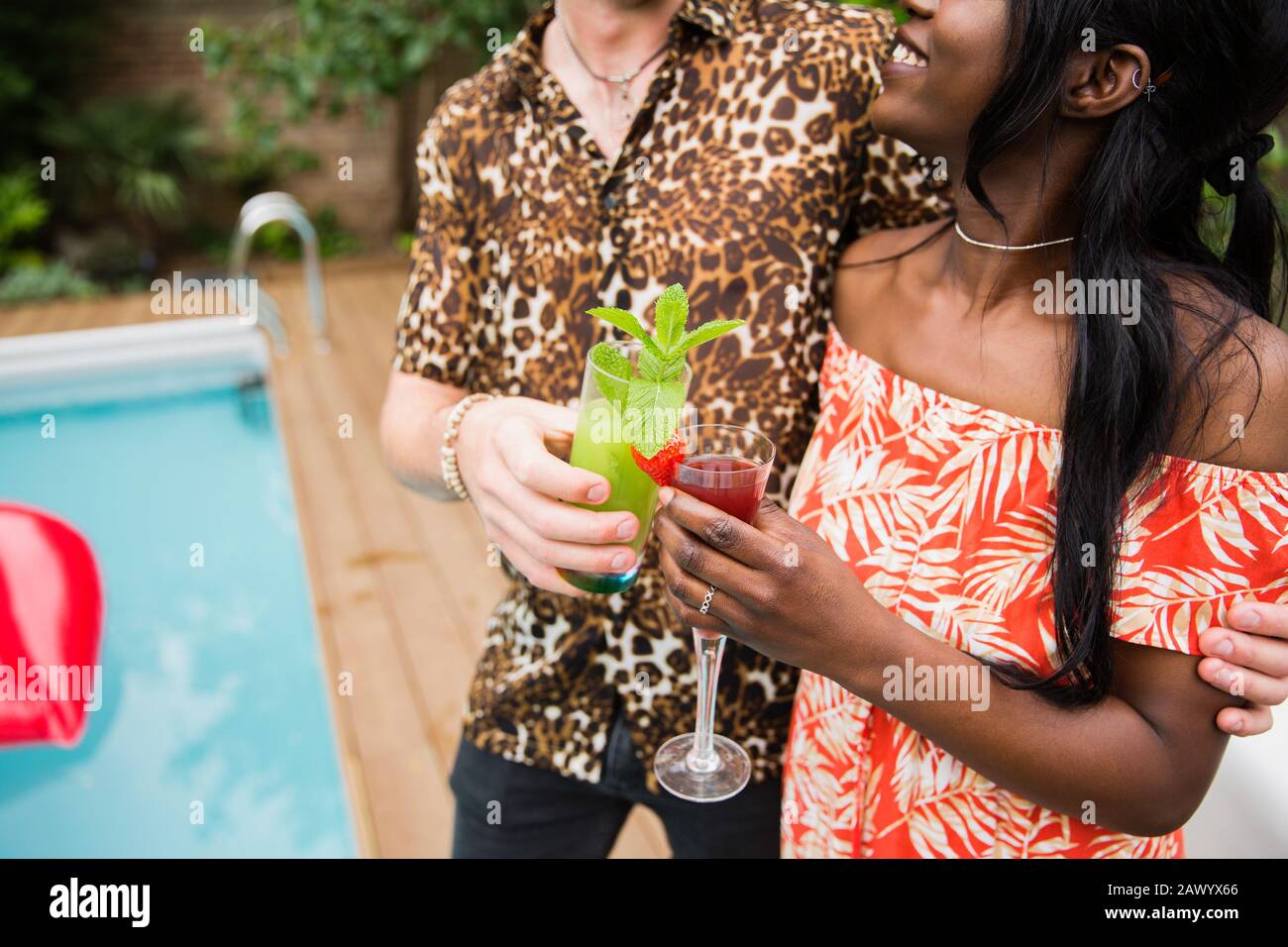 Giovane coppia che beve cocktail a bordo piscina Foto Stock