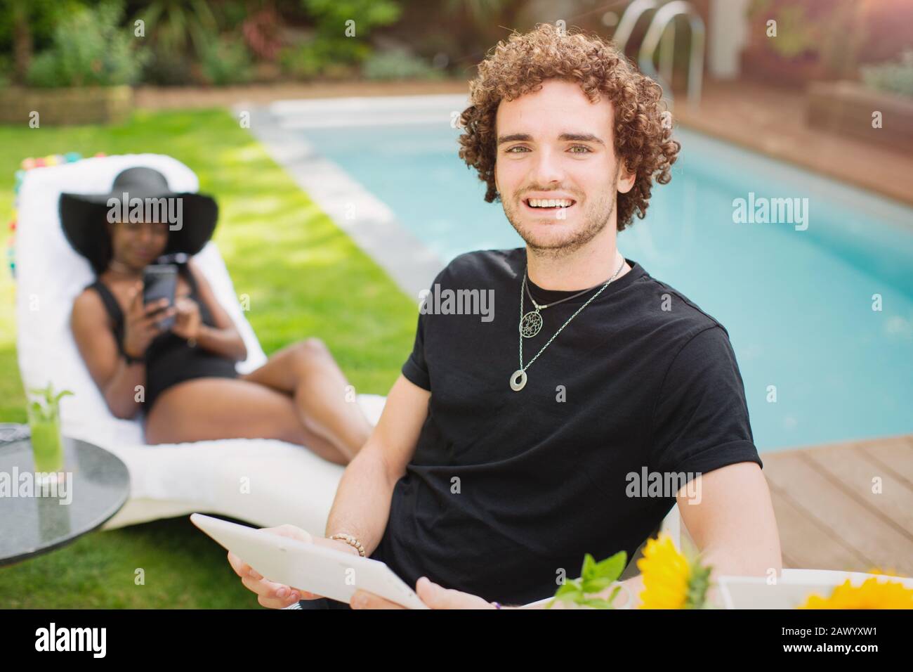 Ritratto giovane felice con tablet digitale a bordo piscina Foto Stock