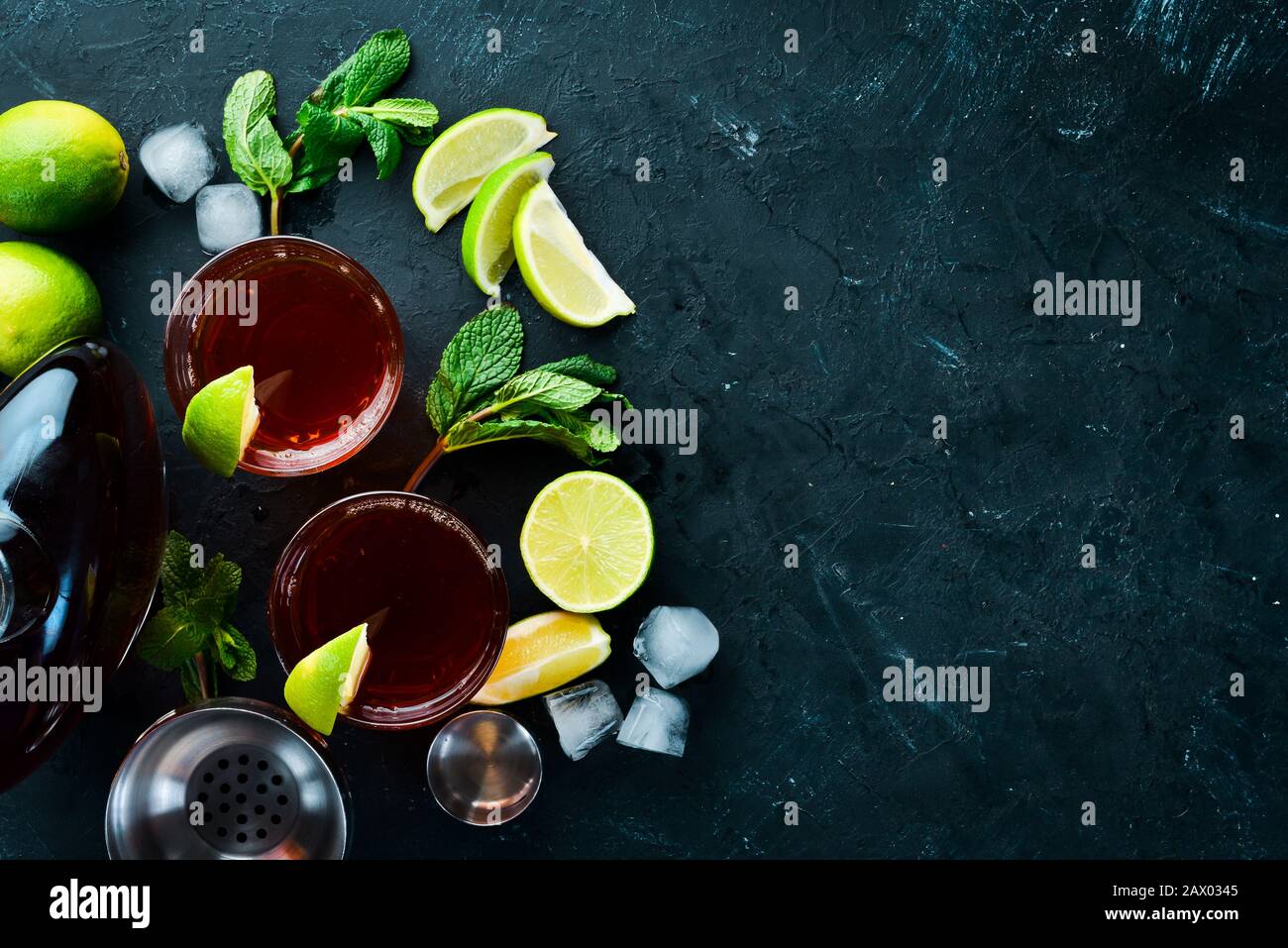 Bevande alcoliche Rum, lime e menta su sfondo di pietra nera. Vista dall'alto. Spazio libero per il testo. Foto Stock