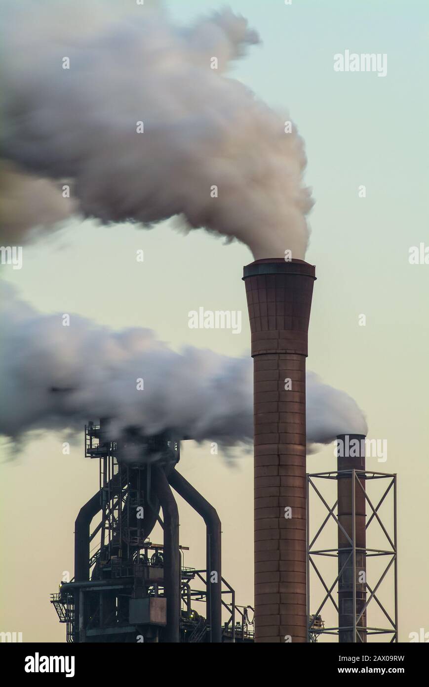 Inquinamento atmosferico di una fabbrica con diversi camini di sera Foto Stock