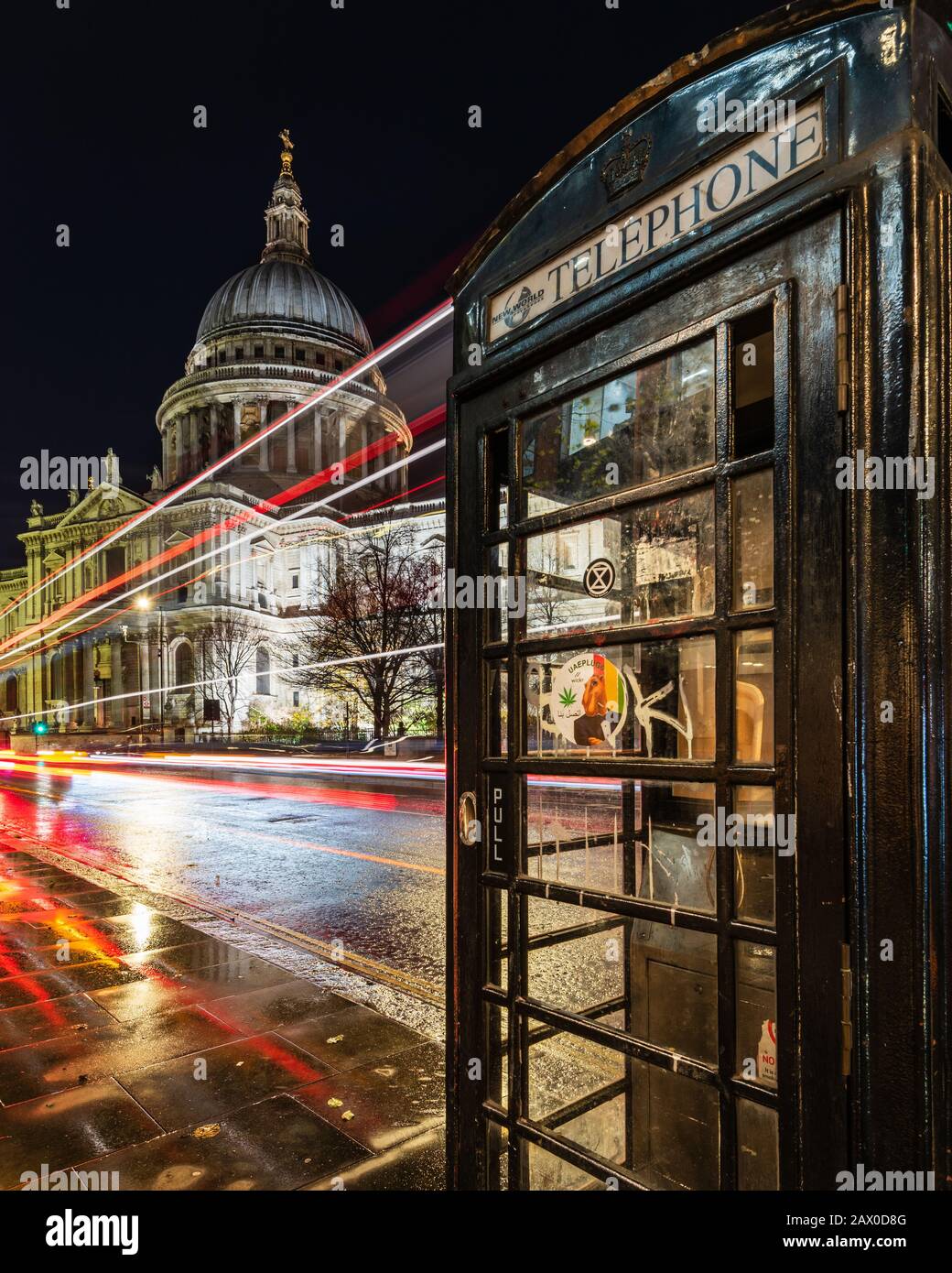 Telefono Box di fronte alla cattedrale di St Paul a Londra con sentieri leggeri dagli autobus di Londra Foto Stock