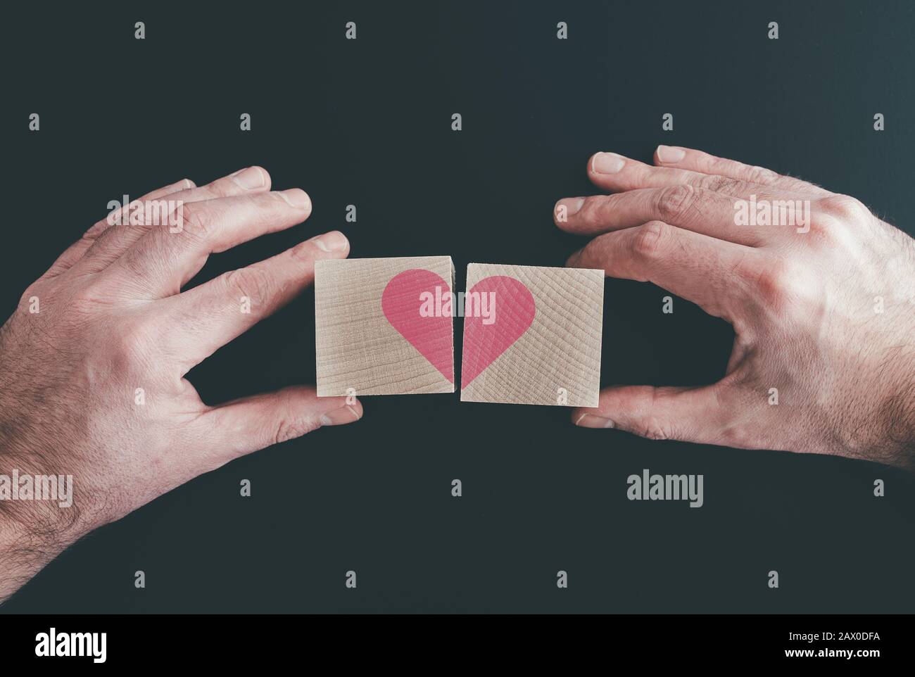 mani che collegano o scollegano blocchi a disco con cuore rosso, amore o cuore rotto Foto Stock
