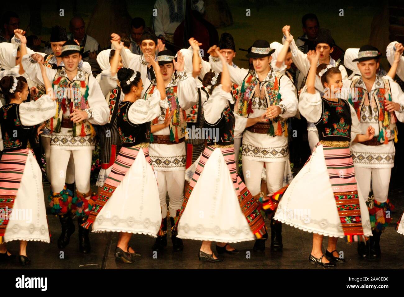 I ballerini professionisti del Banatul Folklore Ensemble tengono le mani in una danza tradizionale rumena indossando costumi tradizionali belli. Foto Stock