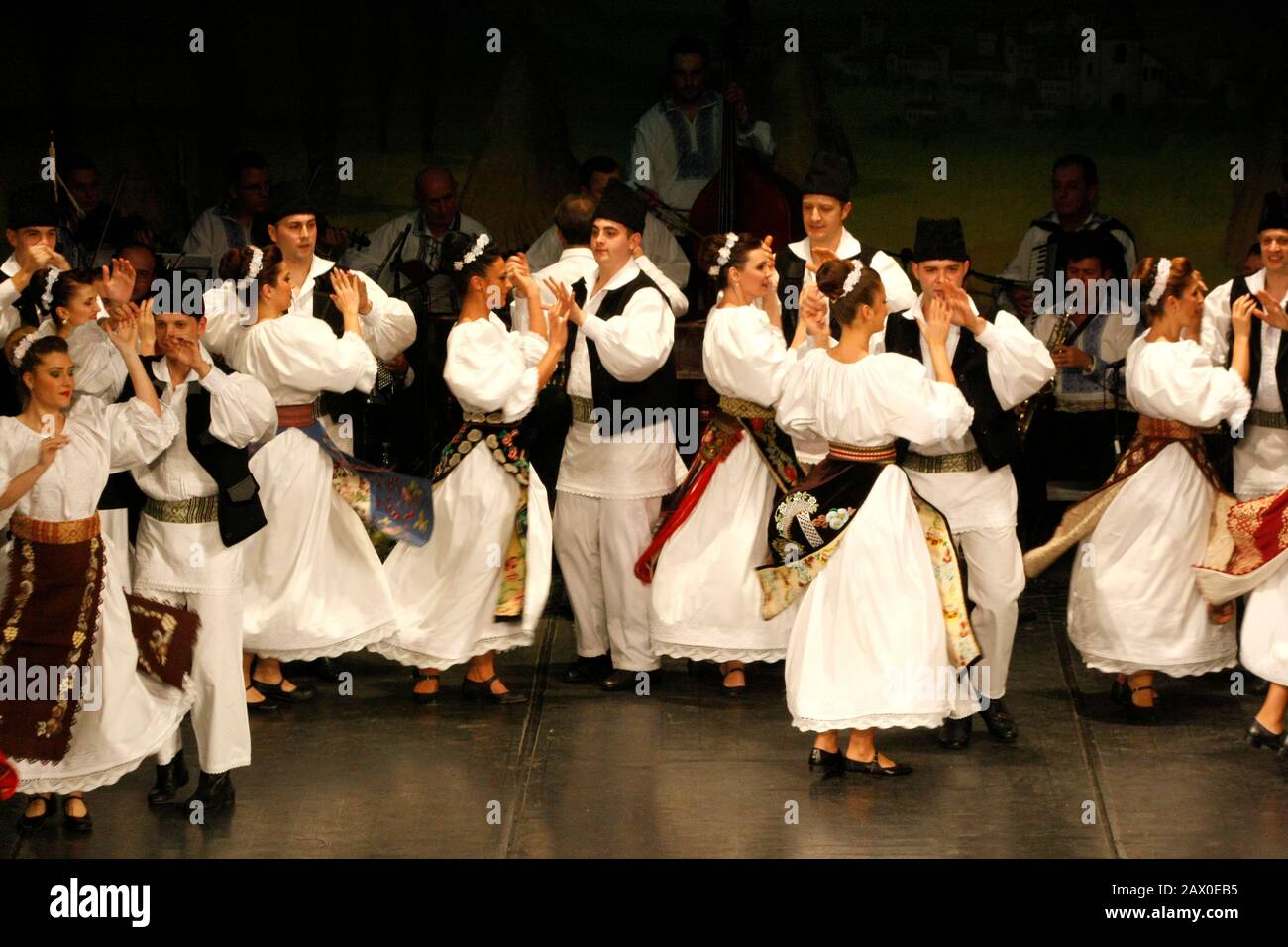 I ballerini professionisti del Banatul Folklore Ensemble tengono le mani in una danza tradizionale rumena indossando costumi tradizionali belli. Foto Stock