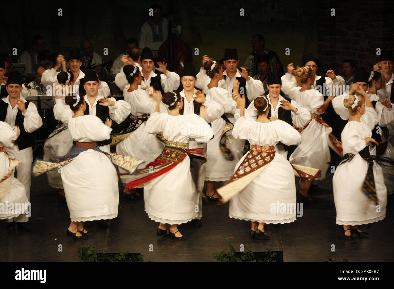 I ballerini professionisti del Banatul Folklore Ensemble tengono le mani in una danza tradizionale rumena indossando costumi tradizionali belli. Foto Stock