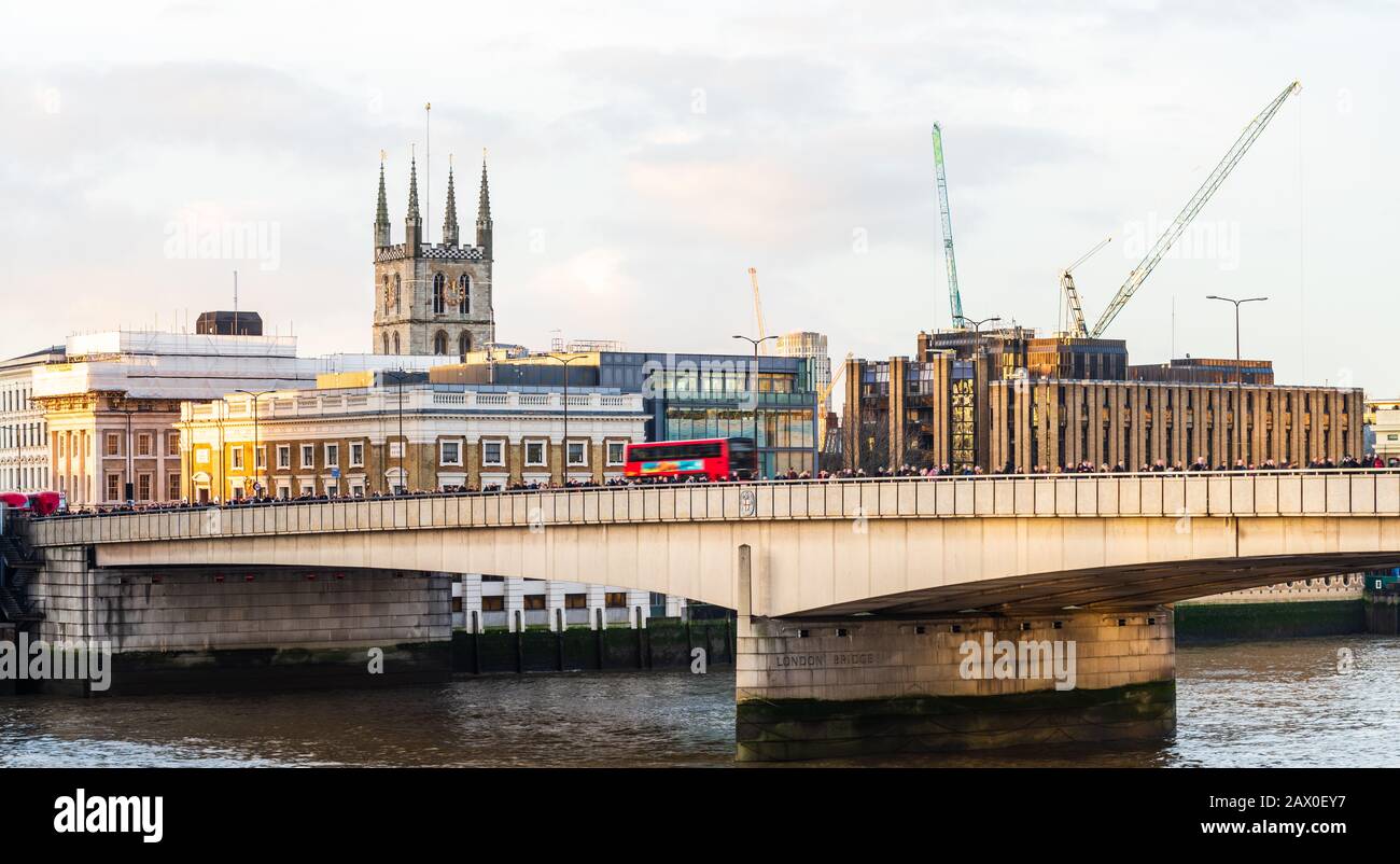 Pendolari che camminano sul London Bridge con un percorso rosso che passa davanti a un maestro Foto Stock