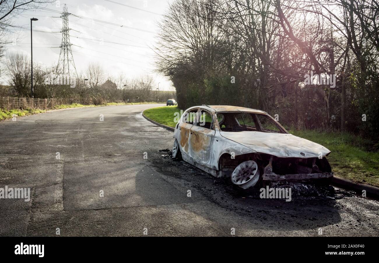 Un'auto bruciata lasciava abbandonata sul lato stradale di una tranquilla zona rurale. Foto Stock