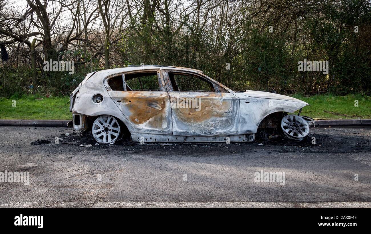 Un'auto bruciata lasciava abbandonata sul lato stradale di una tranquilla zona rurale. Foto Stock