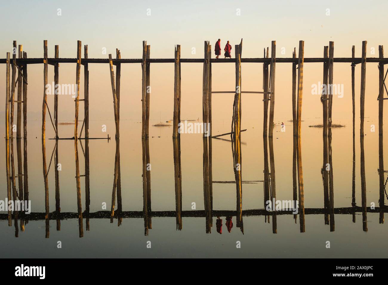 Monaci buddisti che attraversano U Bein Bridge all'alba a Mandalay, Myanmar (Birmania). Foto Stock