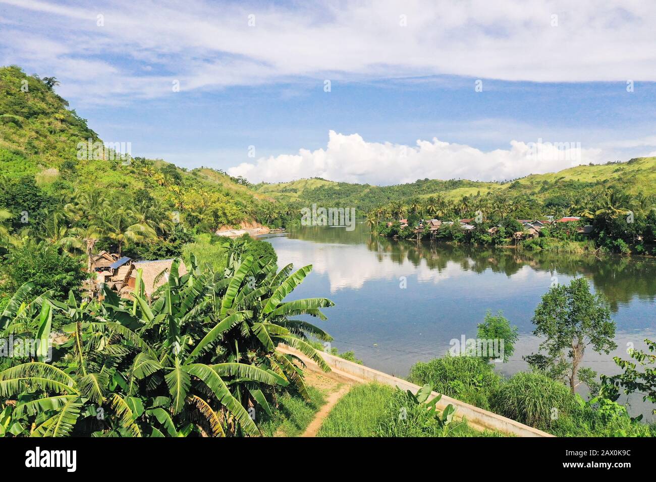 Fiume e colline verdi. Bellissimo paesaggio naturale del fiume nel sud-est asiatico. Campagna su una grande isola tropicale. Piccolo villaggio sulle verdi colline vicino al fiume. La natura delle Filippine. Foto Stock