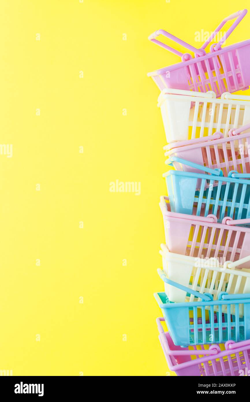 Mucchio di cestini colorati dello shopping di plastica su uno sfondo giallo. Orientamento verticale Foto Stock