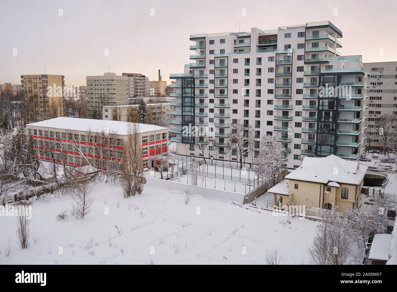 Nuovo edificio di appartamenti a Bucarest, Romania, in inverno, accanto agli edifici più vecchi, sotto la luce soffusa del tramonto. Foto Stock