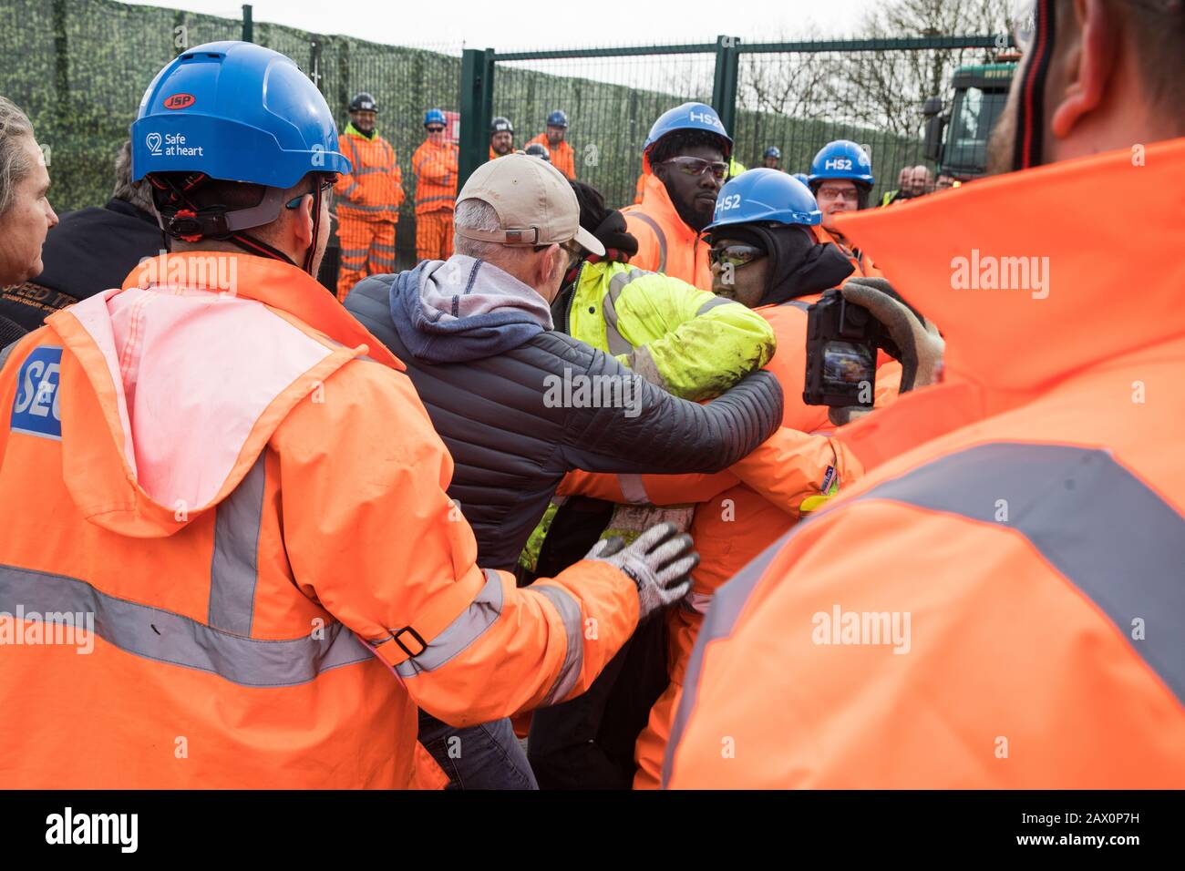 Harefield, Regno Unito. 8 Febbraio 2020. Gli ingegneri HS2 cercano di bloccare gli attivisti ambientali che avevano strisciato attraverso un fosso sotto una chiusura stradale implementata dagli ingegneri HS2 su Harvil Road nella Valle di Colne per facilitare i lavori di abbattimento degli alberi per il progetto ferroviario ad alta velocità. Gli attivisti ambientali che hanno sede in una serie di campi di protezione della fauna selvatica nella zona hanno impedito le opere di abbattimento degli alberi per la durata del fine settimana per il quale sono stati programmati. Credit: Mark Kerrison/Alamy Live News Foto Stock