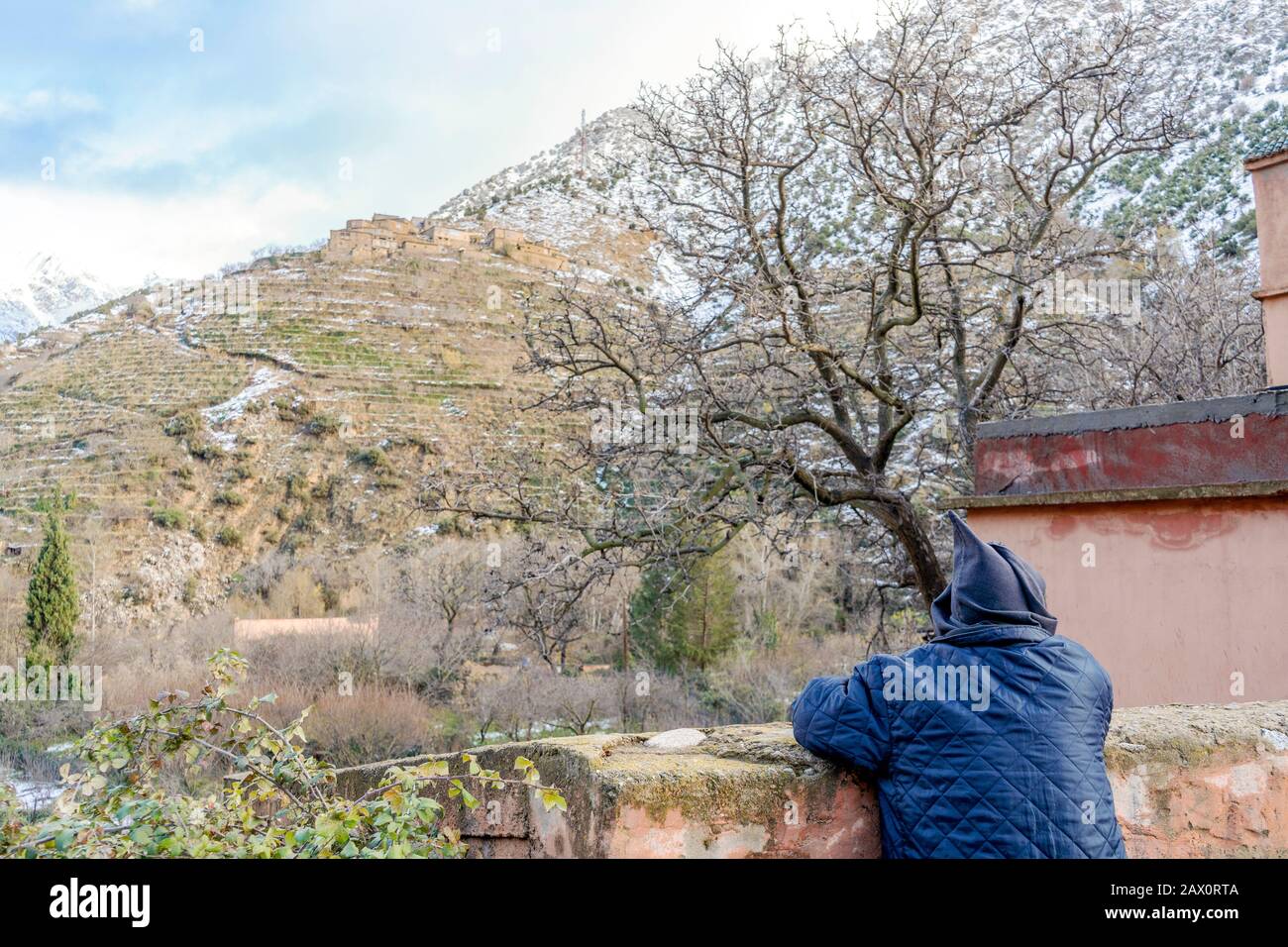 Berber uomo che riposa sulla strada in abiti tradizionali con cappuccio nella valle di Ourika, Marocco Foto Stock