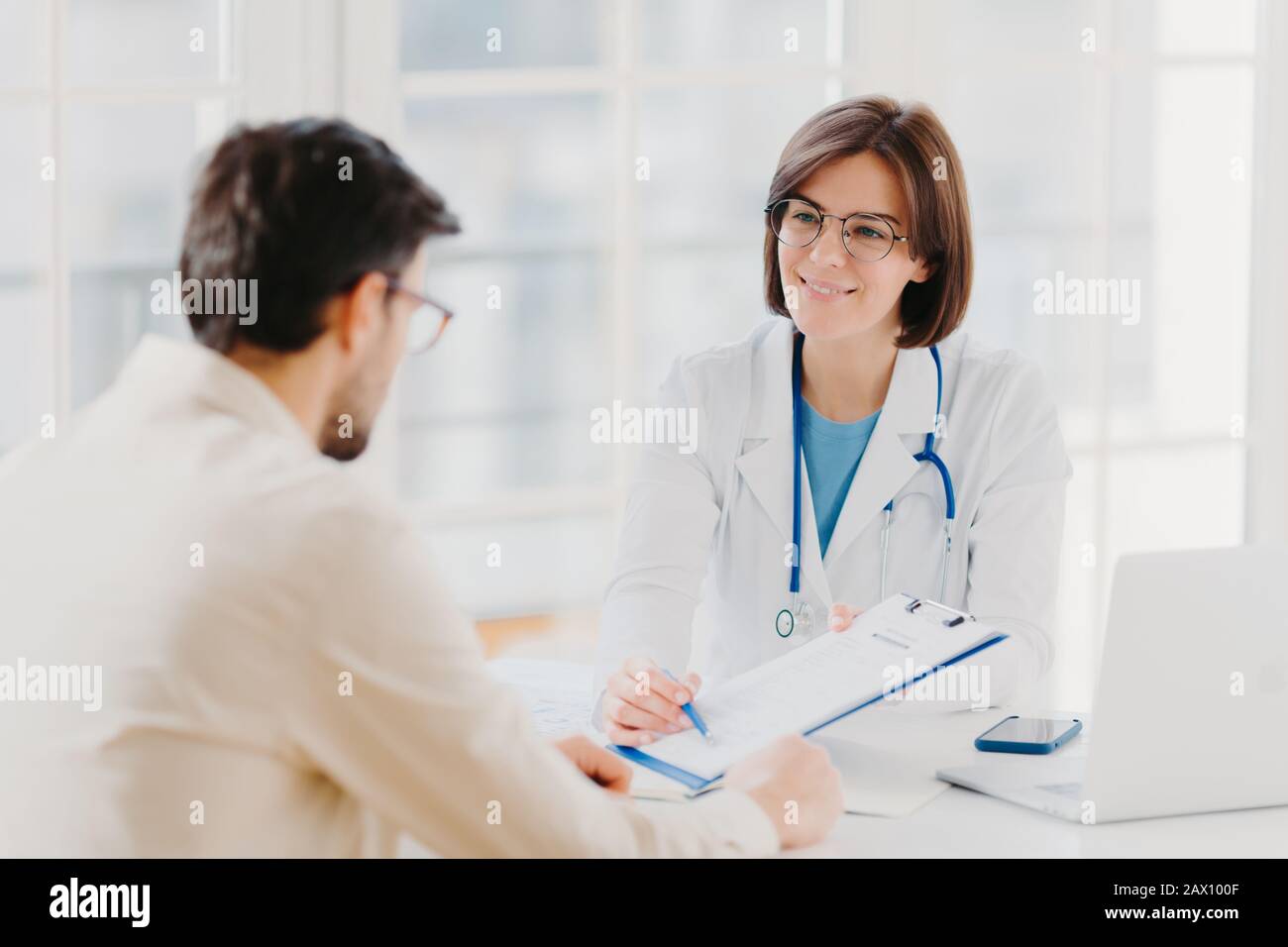 Medico donna che mostra un giovane paziente di sesso maschile i risultati  di laboratorio su una tavoletta digitale in clinica Foto stock - Alamy