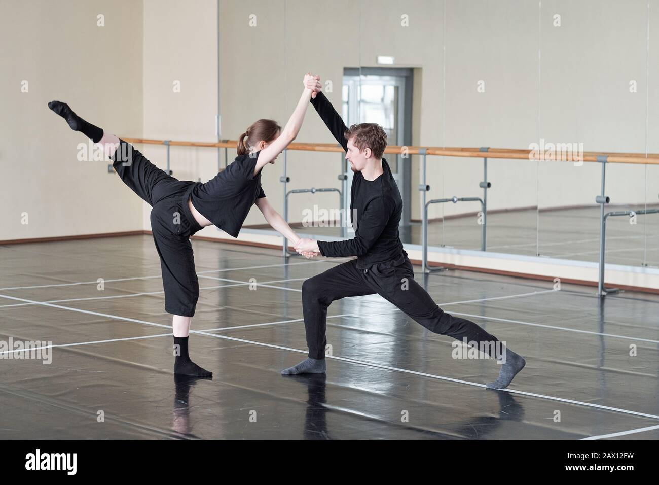 Giovane uomo e donna in nero che prova danza contemporanea partner in studio, scatto orizzontale Foto Stock