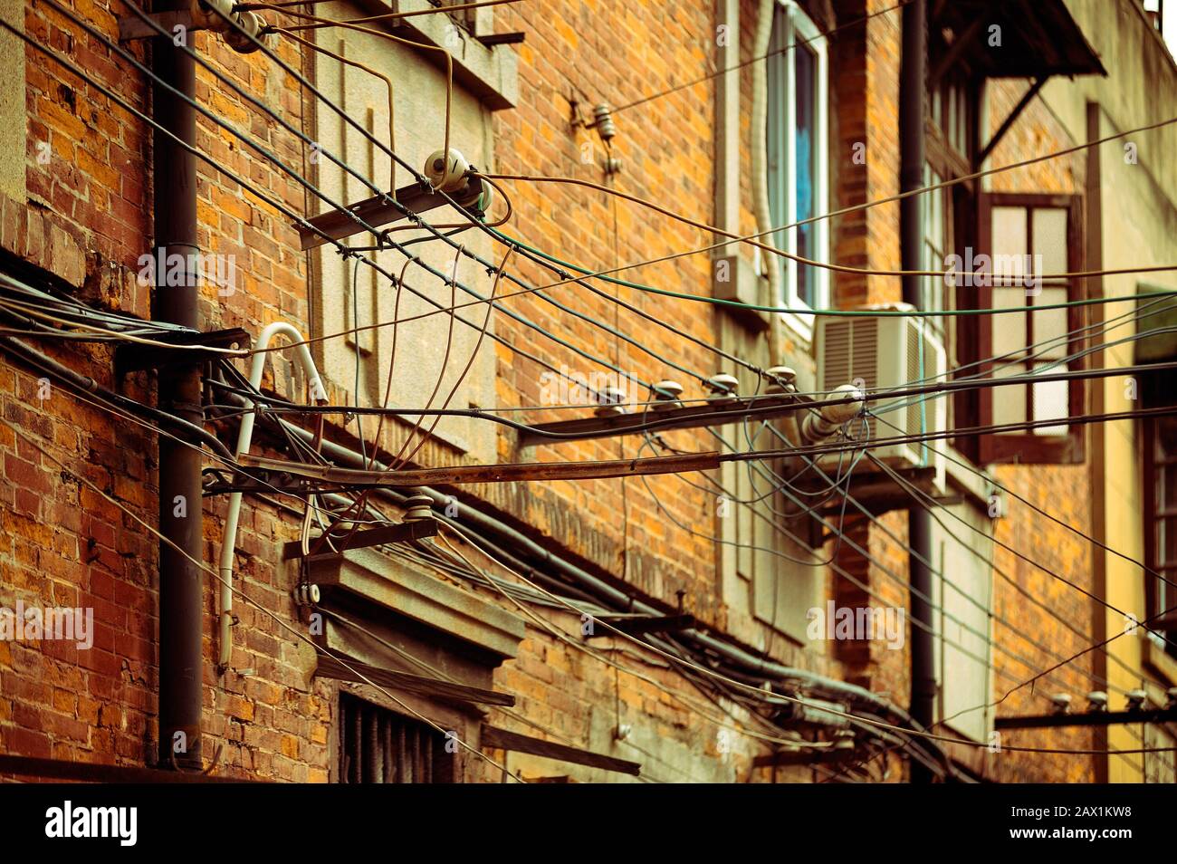 Rete elettrica obsoleta, vecchi fili fissati alla facciata dell'edificio in mattoni. Shanghai, Cina. Foto Stock