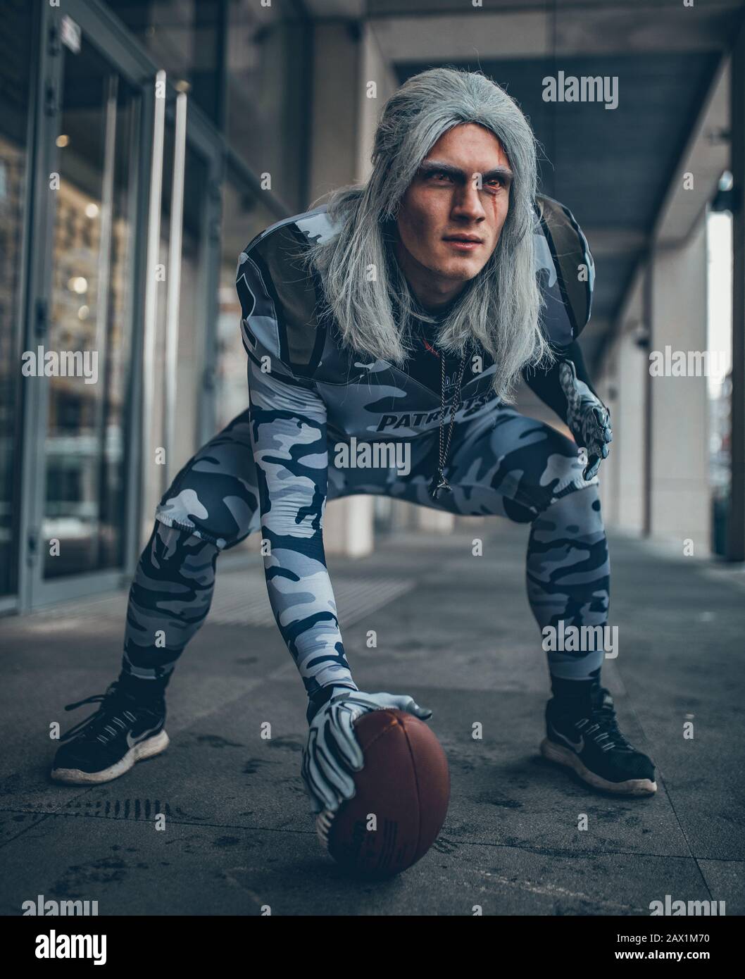 Uomo vestito da calciatore americano con palla in mano. Foto Stock