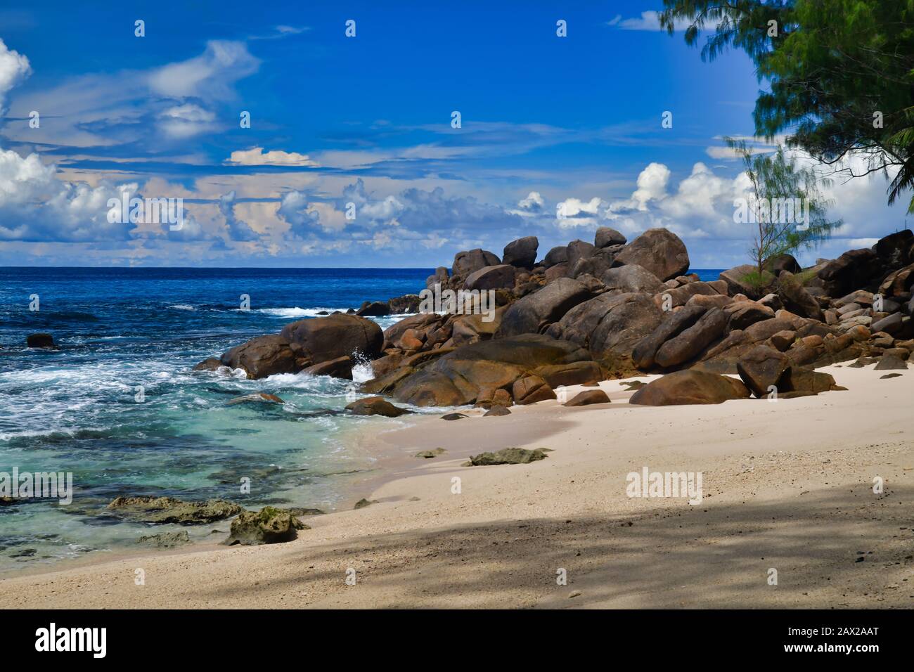 Ocean Waves e rocce di granito Takamaka spiaggia, Mahe Island, Seychelles. Palme, sabbia, onde che si infrangono, bella riva, cielo blu e acqua turchese Foto Stock