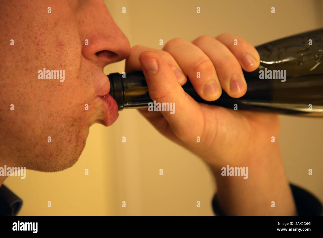 Un uomo caucasico bianco bevendo vino da una casa di bottiglia da solo. Triste modo di passare il tempo, comune per persone sole, depresse e alcoliche. Foto Stock
