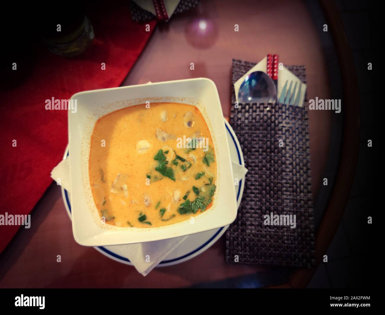 Zuppa di curry rosso di pollo con latte di cocco in stile asiatico nel ristorante vietnamita. Accanto ad esso ci sono le bacchette di cibo e salsa agrodolce. Foto Stock