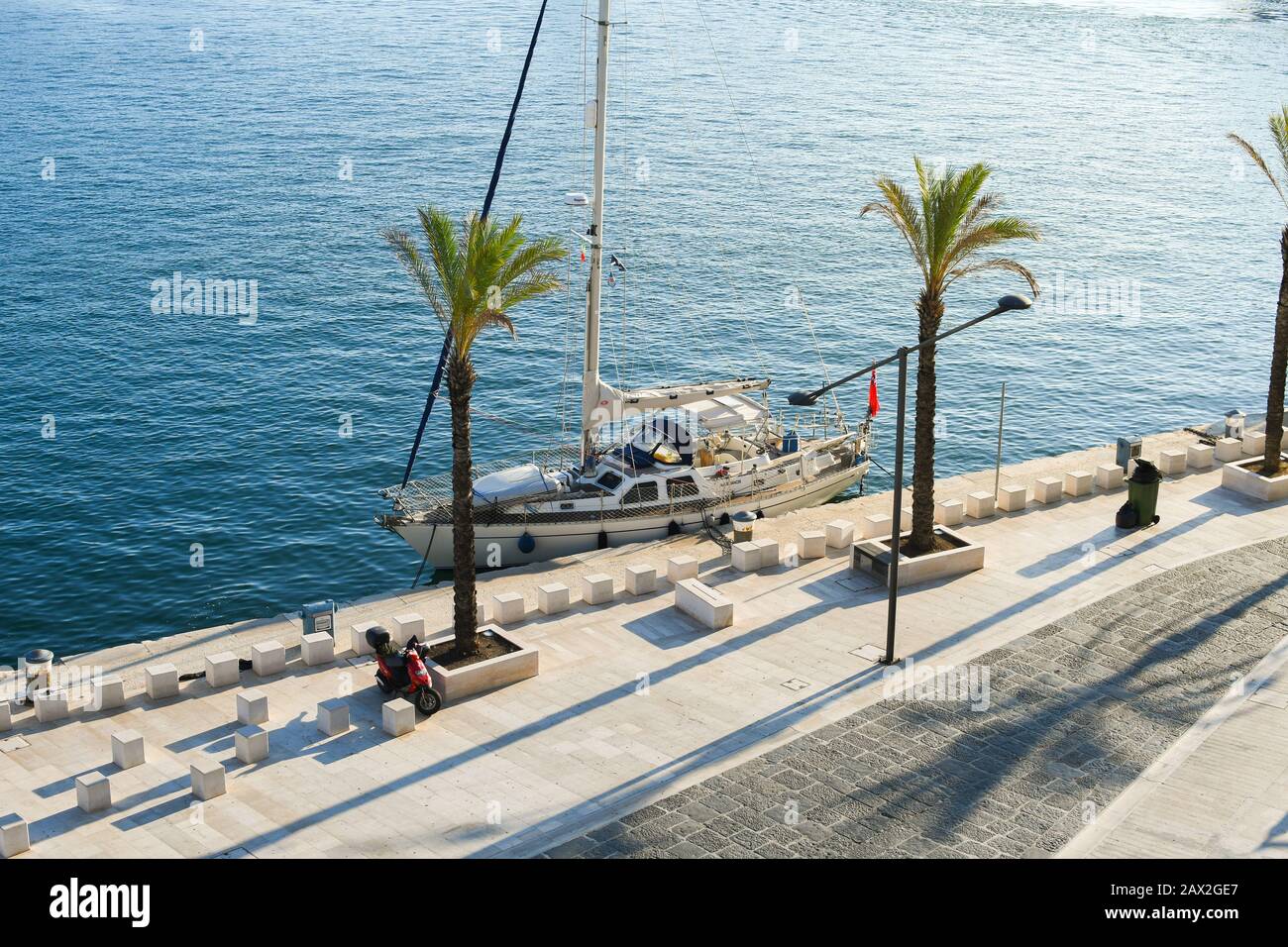 Una barca a vela ormeggia lungo il porto sul lungomare della città portuale di Brindisi, in Italia, nella regione Puglia. Foto Stock
