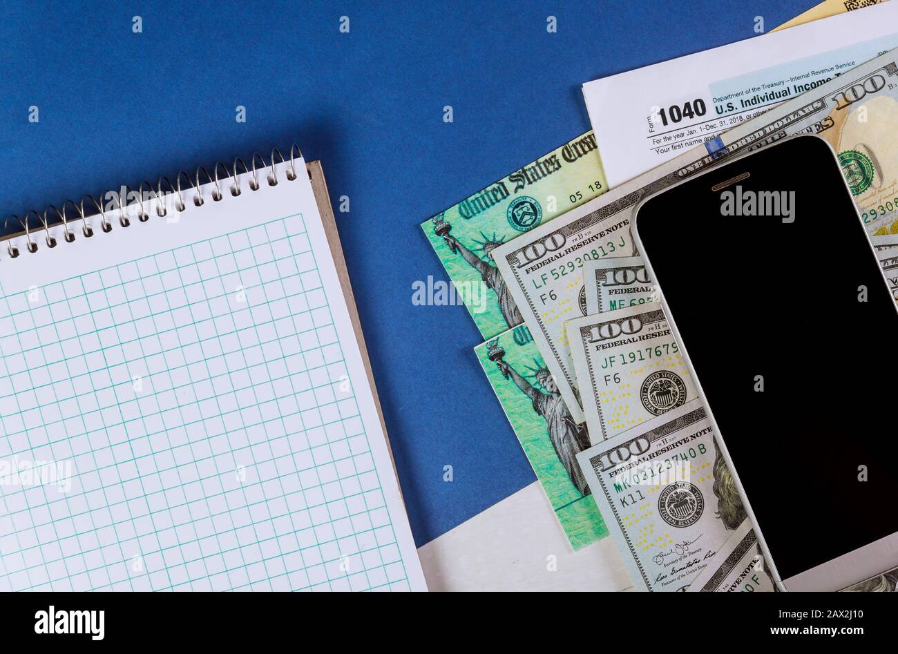 Closeup 1040 modulo fiscale con assegno di rimborso e valuta US banconote in dollari cellulare Foto Stock