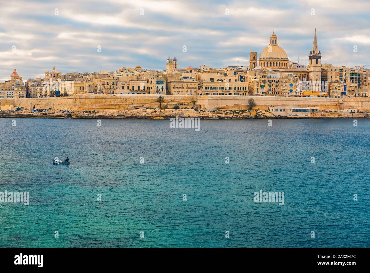 Skyline della città vecchia di la Valletta con pescatore in barca nel porto durante l'alba. Malta, Europa Foto Stock
