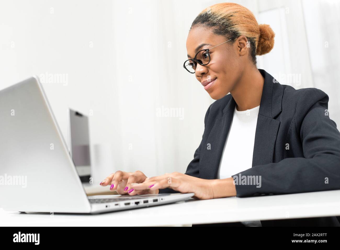 Business African American giovane donna che lavora in ufficio a notebook. Black girl manager utilizza un computer sul posto di lavoro. Foto Stock