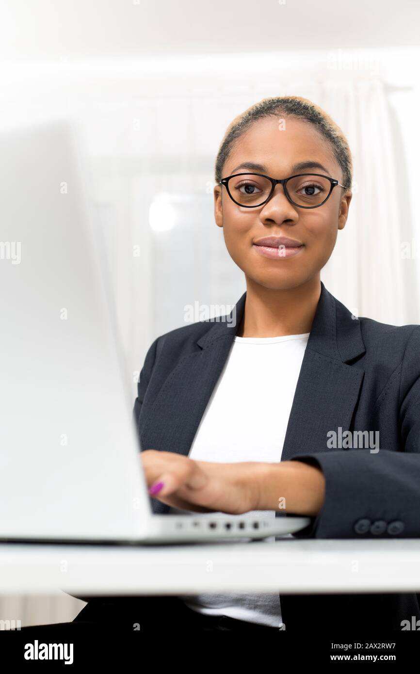 Business African American giovane donna che lavora in ufficio a notebook. Black girl manager utilizza un computer sul posto di lavoro. Foto Stock