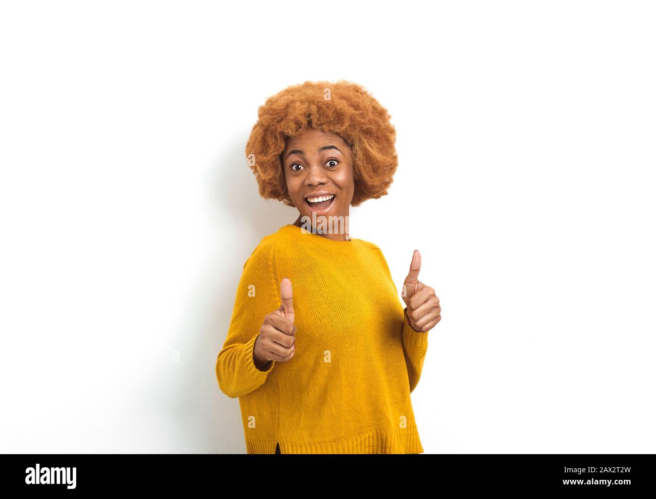 Ritratto di una giovane donna afroamericana sorridente che mostra pollici in su. Foto Stock